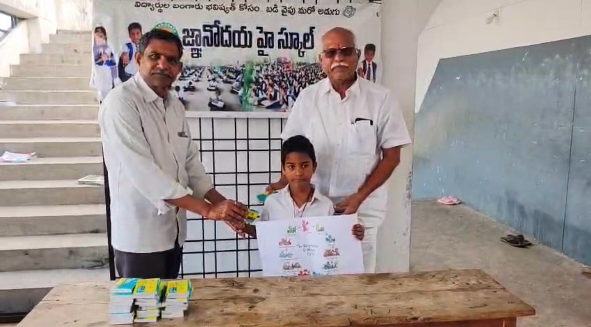 A student receives E-Waste Cycle booklets from school officials at Jnanodaya High School, with a stack of booklets on the table.